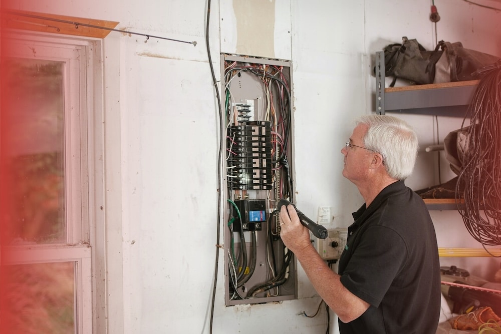 Electrical Panel Inspection Guide 2 An inspector uses a flashlight to examine the internal wiring of an open electrical breaker panel.